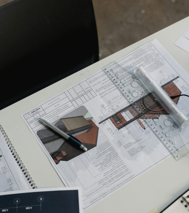 Top view of architectural blueprints and drafting tools on a workspace desk.